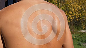 Muscles of the back of a sexy, sunburnt pumped up young worker. Sweat on back, bare torso