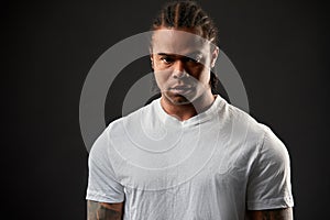 Muscular African American, portrait on a black background of an athletic black guy with dreadlocks on his head