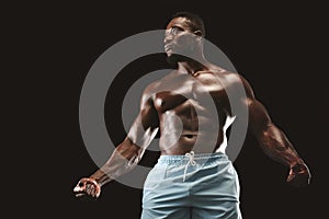 Muscular african american young sportsman over black background