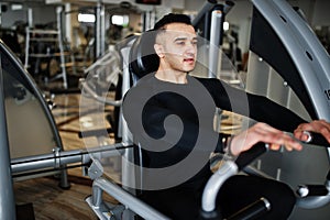 Muscular arab man training and doing workout on fitness machine in modern gym