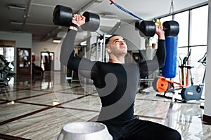 Muscular arab man training with dumbbells in modern gym