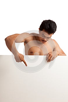 Muscular Asian man point down behind blank sign