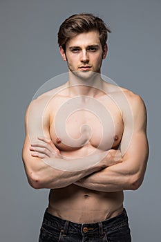 Muscular athlete bodybuilder man with a naked torso on a gray background