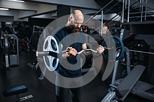 Muscular athlete doing exercise with barbell
