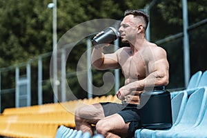 muscular athlete male drinking protein whey cocktail after exercising outdoor