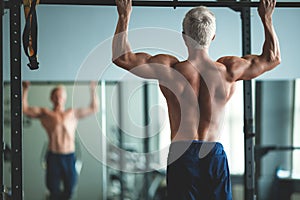 Muscular athlete man making Pull-up in gym. Bodybuilder training in fitness club showing his perfect back and shoulder