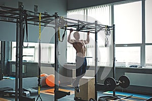 Muscular athlete man making Pull-up in gym. Bodybuilder training in fitness club showing his perfect back and shoulder