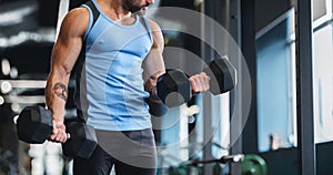 Muscular athlete picking up dumbbells at gym