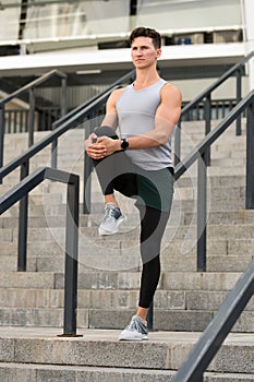 Muscular athlete warming up joints before morning jog