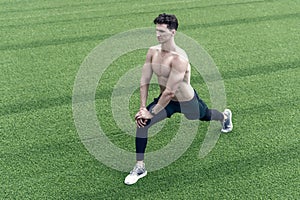 Muscular athlete warming up before workout outdoors, sport concept