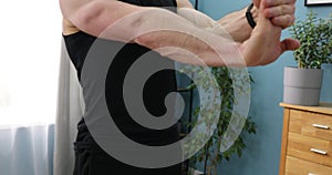 Muscular athlete warms up elbows and hands. Young man athlete practicing hands warming up exercise, preparing for intensive