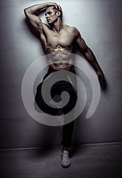 Muscular athlete young man posing over light gray wall