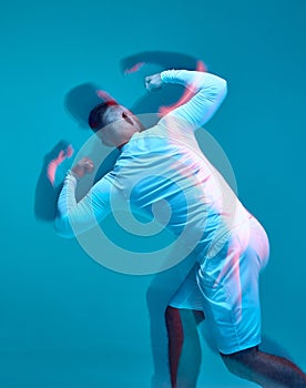 Muscular athletic guy wearing modern sport clothing posing, shows arm triceps muscles. Back view. Long exposure