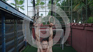 Muscular athletic young man exercising on gymnastic rings. Sport and health care concept