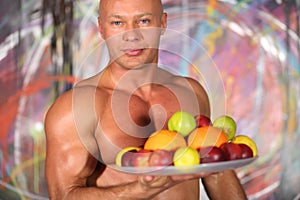 Muscular bald man with a naked torso with a plate