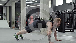 Muscular bearded man does push-ups in gym. Man doing Push Up Exercise in Gym