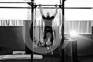 Muscular bearded man training his biceps and back in gym. Pull-ups. Workout lifestyle concept.