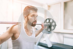 Muscular bearded man during workout in the gym. Bodybuilder doing weight lifting . Close up of young athletic female