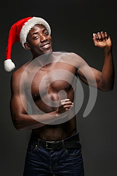 Muscular black shirtless young man in Santa Claus hat