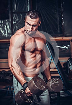Muscular bodybuilder doing exercises with dumbbells
