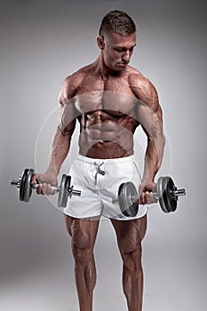 Muscular bodybuilder guy doing exercises with dumbbell