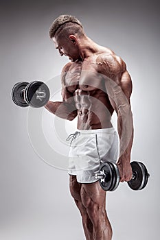 Muscular bodybuilder guy doing exercises with dumbbell