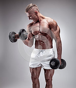 Muscular bodybuilder guy doing exercises with dumbbell