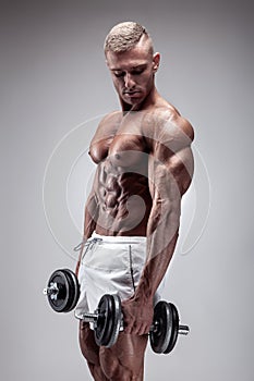 Muscular bodybuilder guy doing exercises with dumbbell