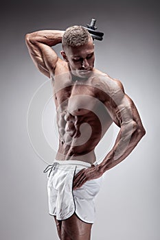 Muscular bodybuilder guy doing exercises with dumbbell