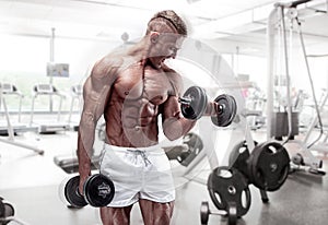 Muscular bodybuilder guy doing exercises with dumbbell