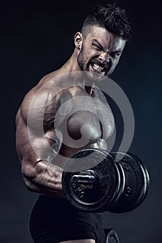 Muscular bodybuilder guy doing exercises with dumbbells