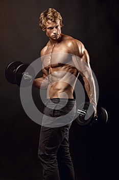 Muscular bodybuilder guy doing exercises with dumbbells