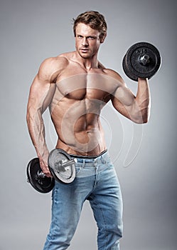 Muscular bodybuilder guy doing exercises with dumbbells