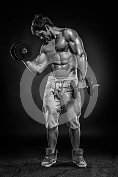 Muscular bodybuilder guy doing exercises with dumbbells over black background