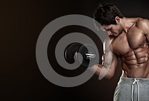 Muscular bodybuilder guy doing exercises with dumbbells over black background