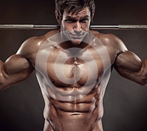 Muscular bodybuilder guy doing exercises with dumbbells over black background