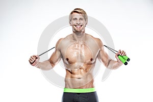 Muscular bodybuilder guy doing exercises with jumping rope