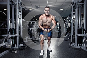 Muscular bodybuilder guy doing exercises workout in gym