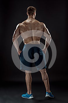 Muscular bodybuilder guy doing posing over black background