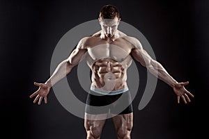 Muscular bodybuilder guy doing posing over black background