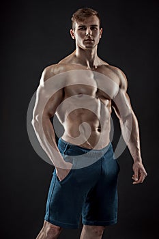 Muscular bodybuilder guy doing posing over black background