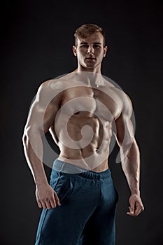 Muscular bodybuilder guy doing posing over black background