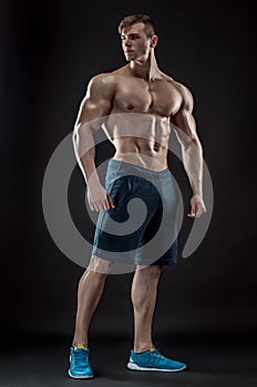 Muscular bodybuilder guy doing posing over black background