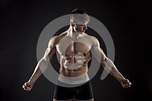 Muscular bodybuilder guy doing posing over black background