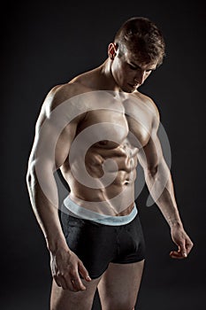 Muscular bodybuilder guy doing posing over black background