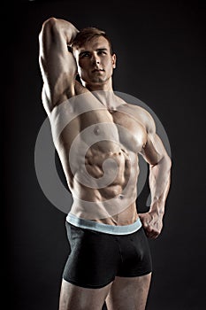 Muscular bodybuilder guy doing posing over black background