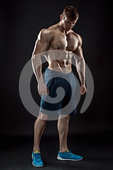 Muscular bodybuilder guy doing posing over black background