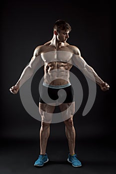 Muscular bodybuilder guy doing posing over black background