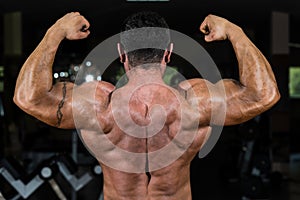 Muscular bodybuilder showing his back double biceps