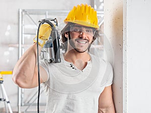 Muscular builder holding a drill over a shoulder